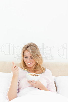 Vertical shot, Woman in bed smiling while looking at a spoon of