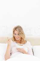 Vertical shot, Woman in bed smiling while looking at a spoon of