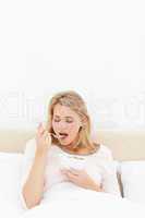 Woman in bed, about to eat a spoon of cereal with eyes closed