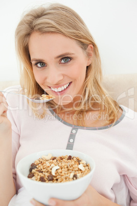 Close up, woman with raised spoon of cereal smiling and looking