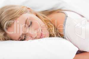 Woman lying in bed, her head on a pillow and eyes closed