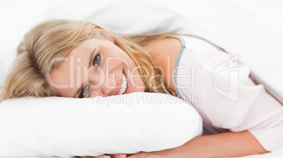 Woman lying in bed, her head on the pillow and eyes open while s