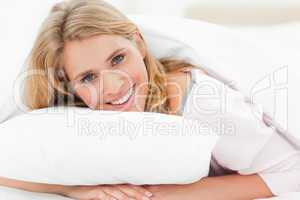 Woman lying in bed, her hands under the pillow, her head raised