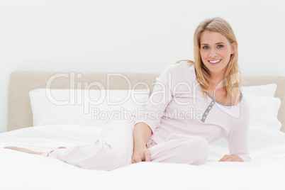 Woman lying across the bed, leaning back slightly and smiling