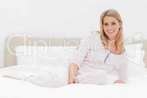 Woman lying across the bed, leaning back slightly and smiling