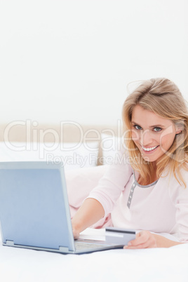 Woman lying on the bed, laptop beside her as she looks forward s