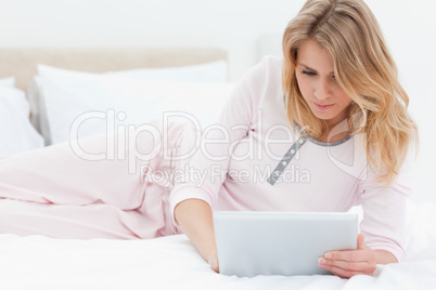 Woman lying on the bed, while using a tablet pc