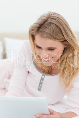 Close up, woman on her tablet pc, lying on the bed and smiling