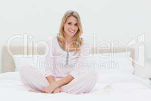 Woman sitting with her legs folded on the bed while smiling