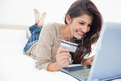 Woman on her laptop with credit card in hand and smiling