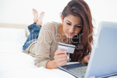 Woman looking at her credit card details as she uses her laptop