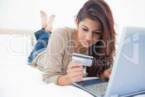 Woman looking at her credit card details as she uses her laptop