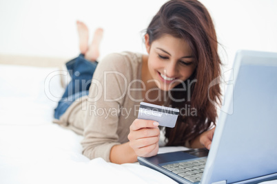 Smiling woman on her laptop reading her credit card details on t