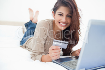 Woman smiling and looking ahead as she uses her laptop, and cred