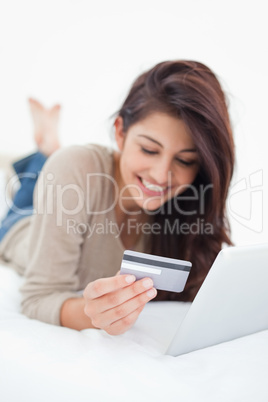 Close up, focusing on credit card, held by a smiling woman on he
