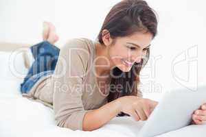 Woman smiling as she scrolls through her tablet on the bed