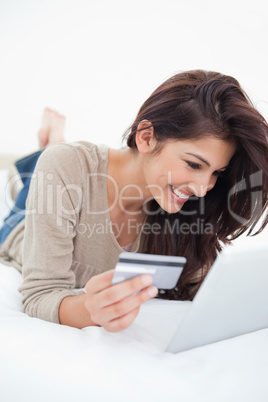 Woman smiling as she uses her tablet and credit card