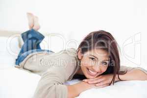 Woman with crossed and raised feet, smiles as she lies on her be