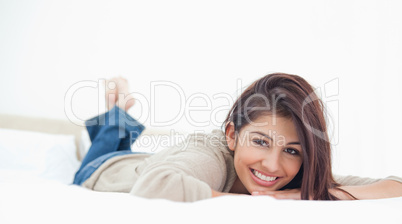 Low angle, woman lying on the bed, smiling with her legs crossed