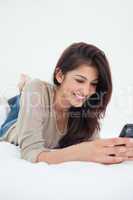 Close up, woman using her phone and smiling while on the bed
