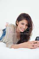 A woman smiling as she looks in front of her with her phone in h