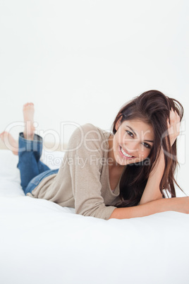 Close up, woman lying on the bed smiling with a hand in her hair