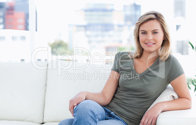 Woman smiling while sitting on couch with crossed legs