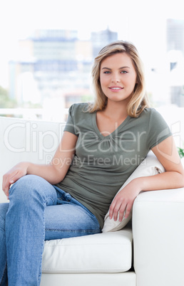 Close up, woman sitting on the couch with crossed legs and a smi