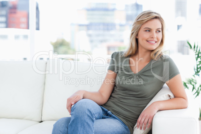 Woman sitting on couch, smiling, legs folded and looking to the