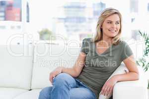 Woman sitting on couch, smiling, legs folded and looking to the