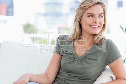 Close up, woman smiling and sitting on the couch looking to the