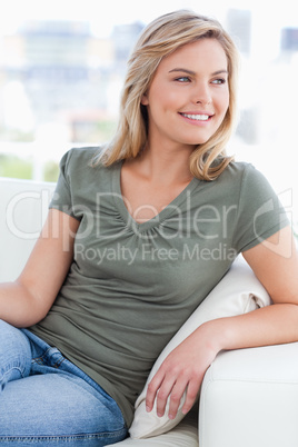 Woman looking to her side while smiling and sitting on the couch