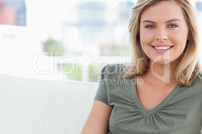 Close up, woman smiling as she sits on a couch