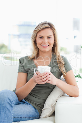 Woman holding a cup, smiling as she looks forward with crossed l