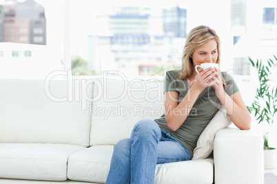 Woman holding a mug up to her nose as she looks to the side whil