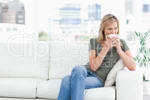 Woman holding a mug up to her nose as she looks to the side whil