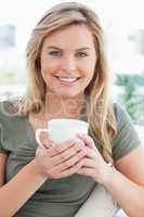 Close up, woman smiling, with mug in her hands and looking ahead