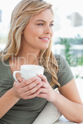 Close up, woman holding a mug in her hands, her head turned to t