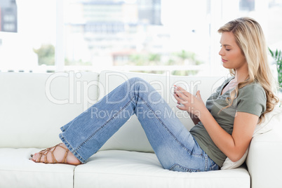 Woman sitting sideways on the couch, cup in hands, and eyes clos