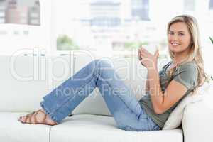 Woman looking forward, smiling with a mug in her hands and sitti