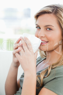 Close up, woman holding a cup to her lips, smiling and looking f