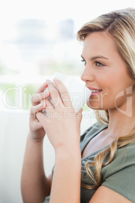 Close up, woman looking sideways, cup in hand and smiling
