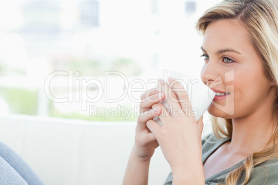 Woman smiling with cup held to her lips and knees raised