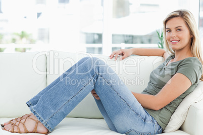 Woman sitting across the couch knees raised, smiling, looking fo