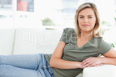 Woman lying across the couch looking forward, with arms on the a
