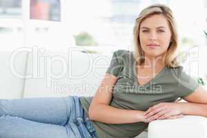 Woman lying across the couch looking forward, with arms on the a