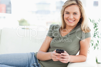 Woman smiling and looking in front of her as she uses her phone