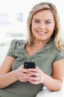 Woman looking forward and smiling as she holds her phone