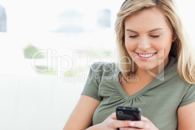 A woman looking at her phone in front of her and smiling