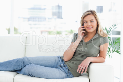 Woman lying across the couch, smiling, looking forward and makin
